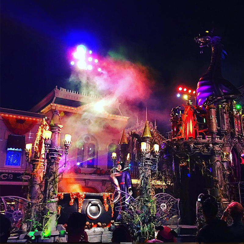Disneyland's haunted mansion at Halloween with colorful lights, a bubbling cauldron, and other spooky decor